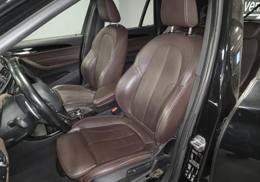 Vue intérieure côté conducteur du BMW X1 xDrive 25d 2016 avec sellerie cuir Dakota marron et tableau de bord noir.