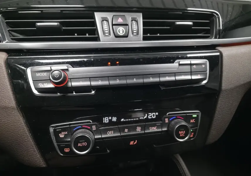 Détail de la console centrale noire brillante du BMW X1 xDrive 25d 2016 avec commandes de climatisation automatique bi-zone.