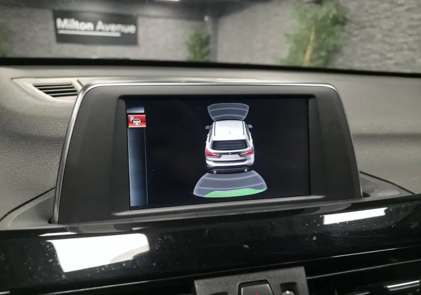 Écran central intérieur montrant l'aide au stationnement avec vue arrière virtuelle du BMW X1 xDrive 25d noir.