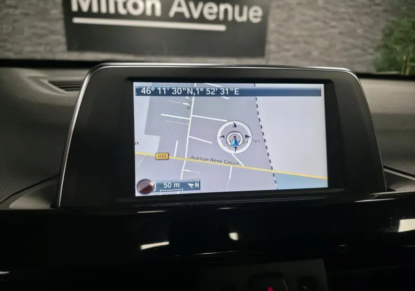 Écran central de navigation GPS dans l'habitacle d'une BMW X1 xDrive 25d noire, vue intérieure.