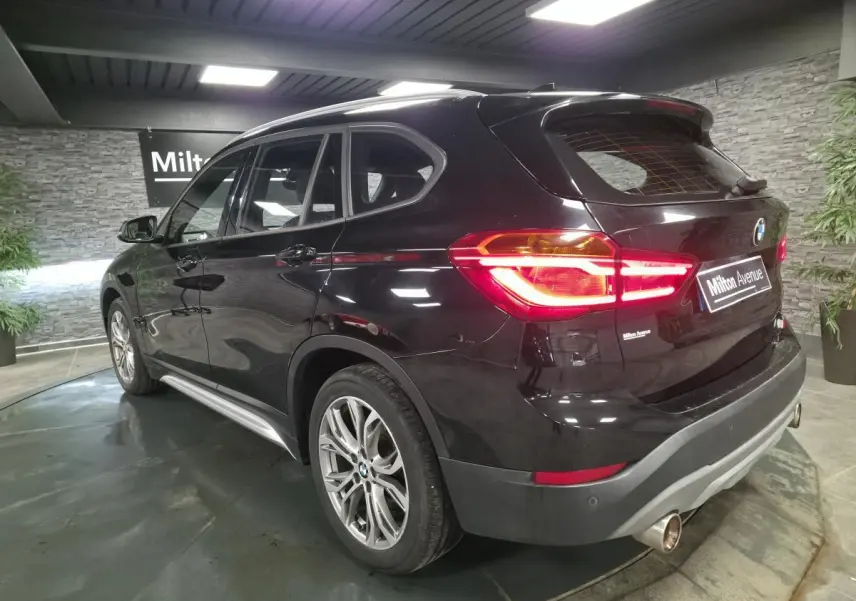 BMW X1 xDrive 25d noir vue 3/4 arrière droit, feux allumés et jantes alliage 18'' style 566 en Y.