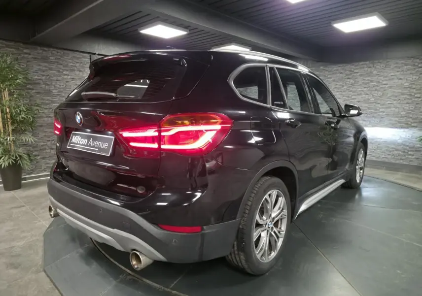 BMW X1 xDrive 25d noir vue 3/4 arrière droit, avec feux allumés et jantes alliage 18 pouces style 566 en Y.