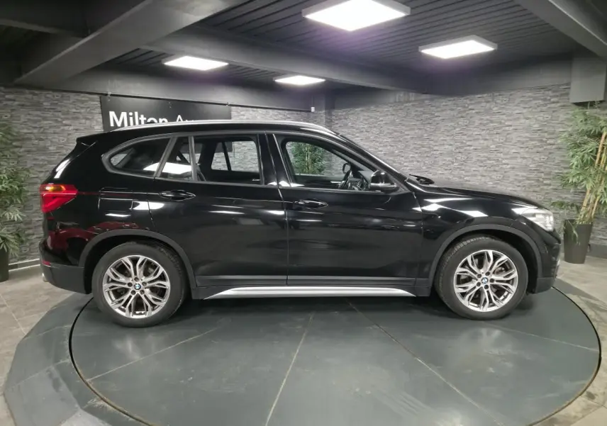 BMW X1 xDrive 25d noir vue de profil côté gauche, avec jantes alliage 18'' style 566 à rayons en Y.