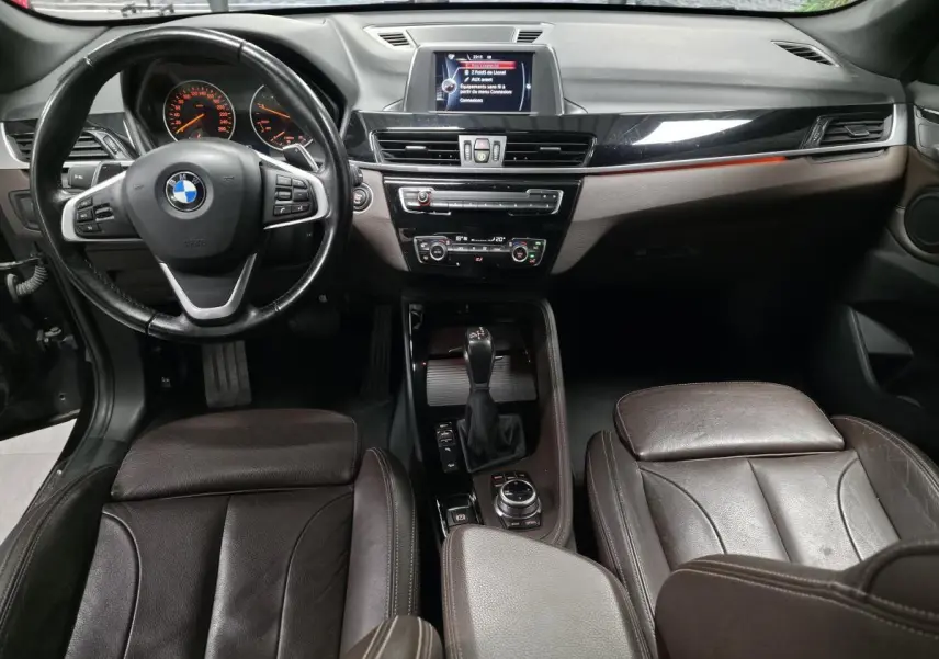 Vue intérieure avant du BMW X1 xDrive 25d 2016, sellerie cuir marron et tableau de bord avec écran central.