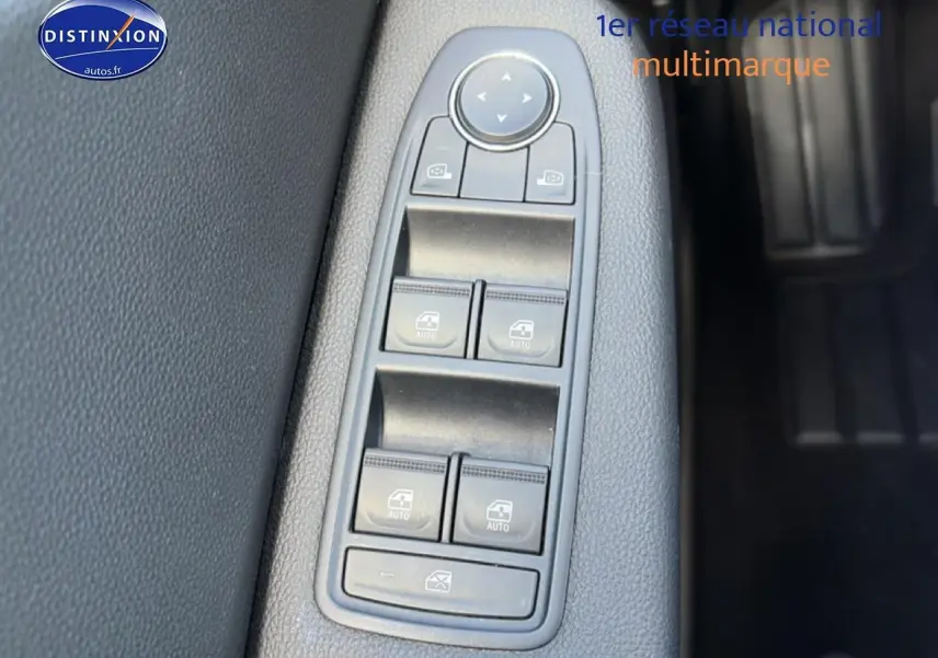 Gros plan sur les commandes de lève-vitres et rétroviseurs électriques sur la porte côté conducteur d'une Renault Clio V gris foncé.