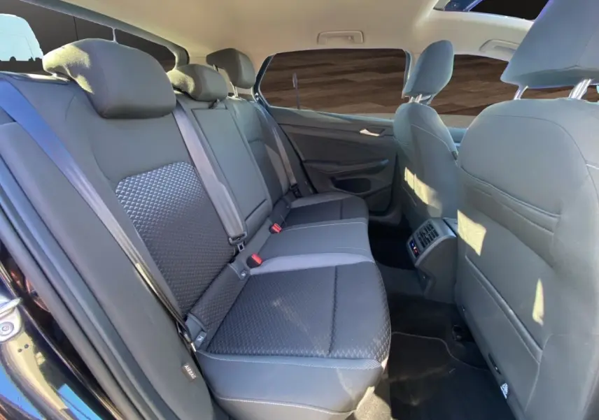 Vue intérieure côté arrière droit de la Volkswagen Golf 2.0 TDI noire, montrant la banquette arrière et les sièges avant.