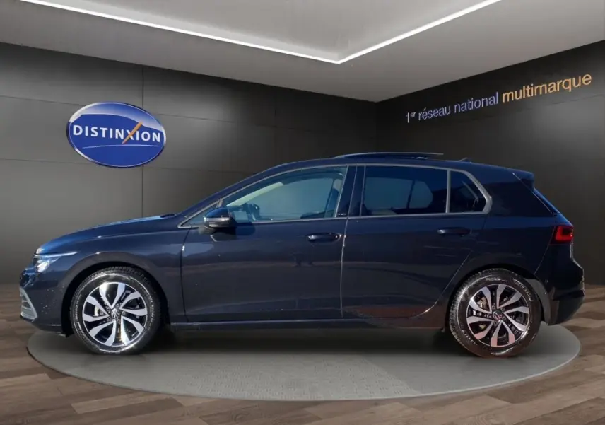Vue de profil côté gauche d'une Volkswagen Golf noire 5 portes, avec jantes alliage et toit panoramique visible.