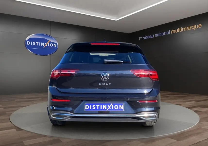 Vue arrière d'une Volkswagen Golf noire 2022 avec feux LED et logo VW bien visibles en showroom.