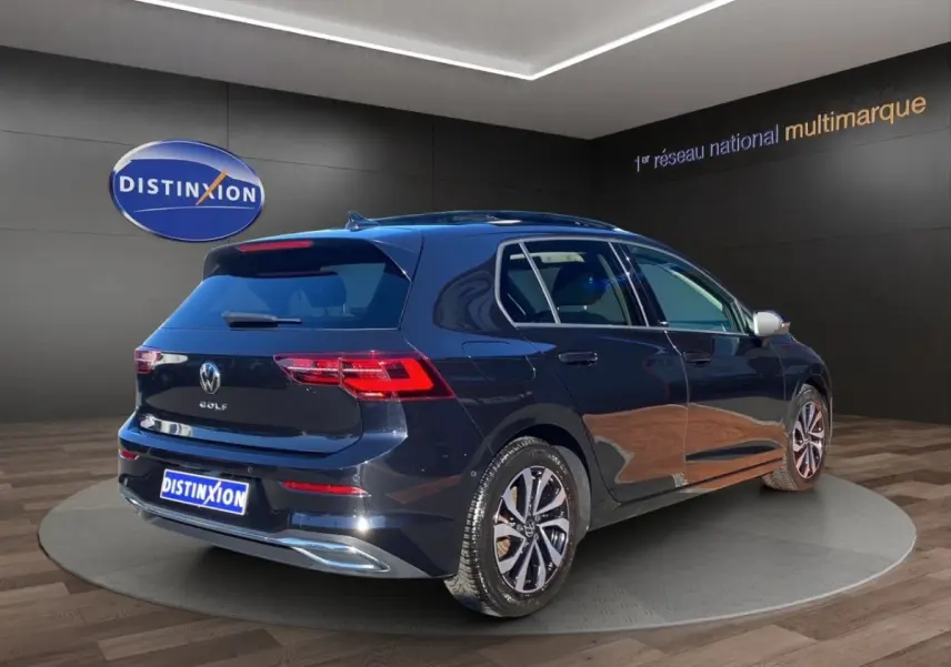 Volkswagen Golf noire vue 3/4 arrière droit en intérieur, avec jantes alliage et toit panoramique.