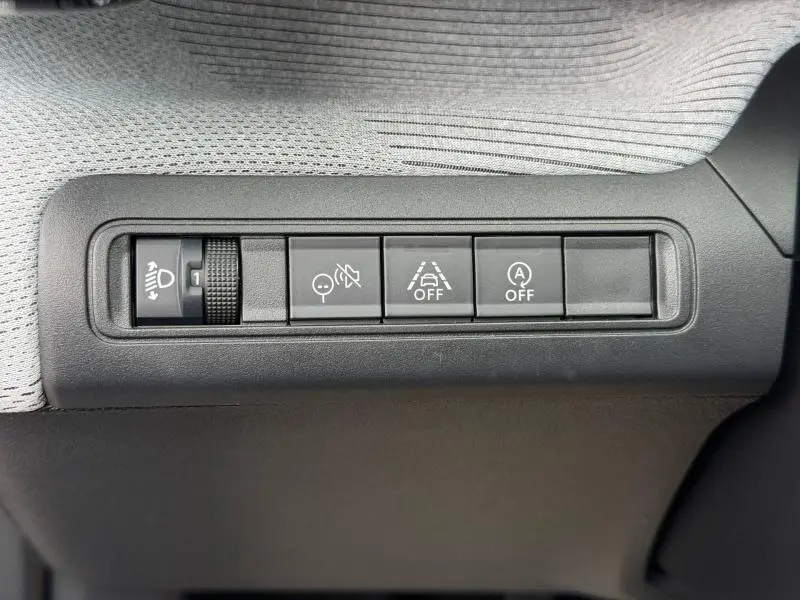 Gros plan sur les commandes de réglage des phares et d'assistance à la conduite dans une Citroën C3 2025 Noir Perla Nera.
