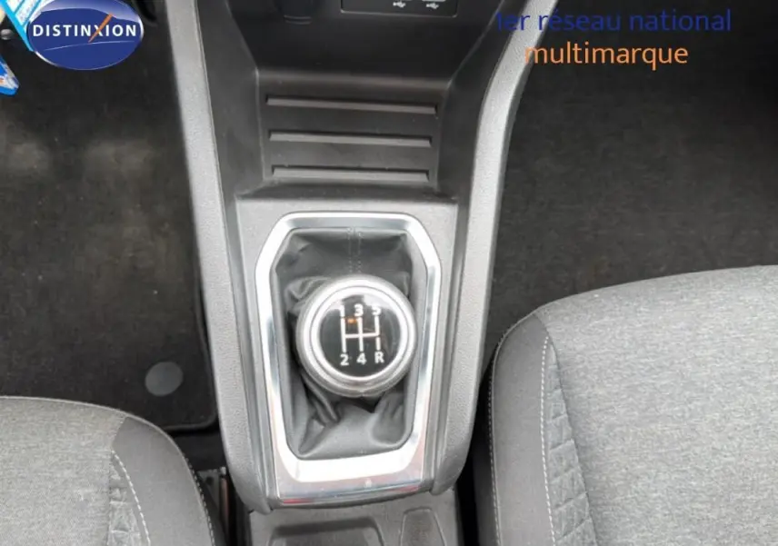 Vue rapprochée du levier de vitesses manuel de la Renault Clio blanche, avec console centrale et sièges gris.