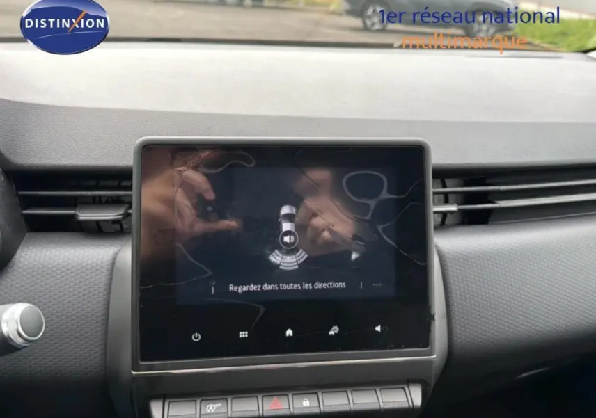 Vue rapprochée de l’écran central tactile du tableau de bord d’une Renault Clio blanche, affichant l’aide au stationnement.