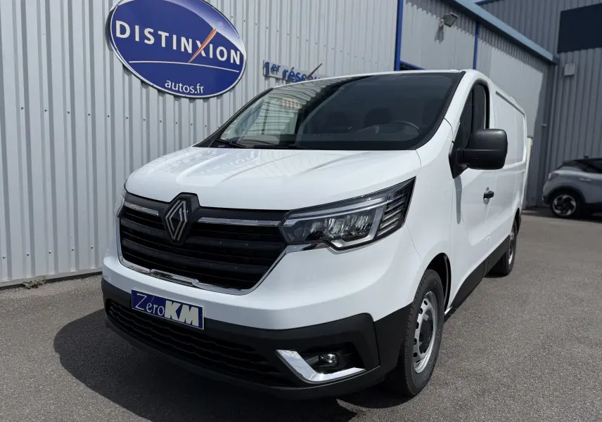 Vue 3/4 avant droite d’un Renault Trafic Fourgon blanc 2025 avec calandre noire et logo Renault proéminent.