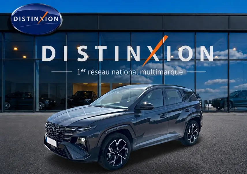 Hyundai Tucson 1.6 T-GDI hybride gris écotronique en 3/4 avant, avec jantes alliage 19 pouces et calandre glossy noire.
