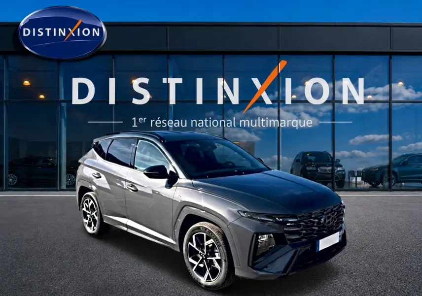 Hyundai Tucson 2026 gris écotronique en 3/4 avant droit avec calandre glossy black et jantes alliage 19 pouces.