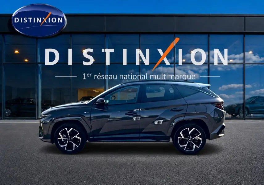 Vue latérale droite du Hyundai Tucson 2026 gris ecotronique avec jantes alliage et détails N Line devant vitrine Distinxion.