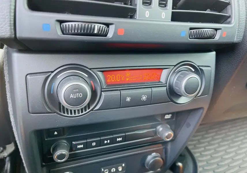 Gros plan sur la console centrale du BMW X6 blanc 2013, affichant la climatisation automatique à 20°C.