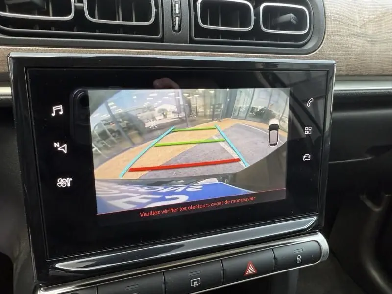 Écran central montrant la caméra de recul d'une Citroën C3 noire toit blanc, avec guidage coloré pour manœuvre en marche arrière.