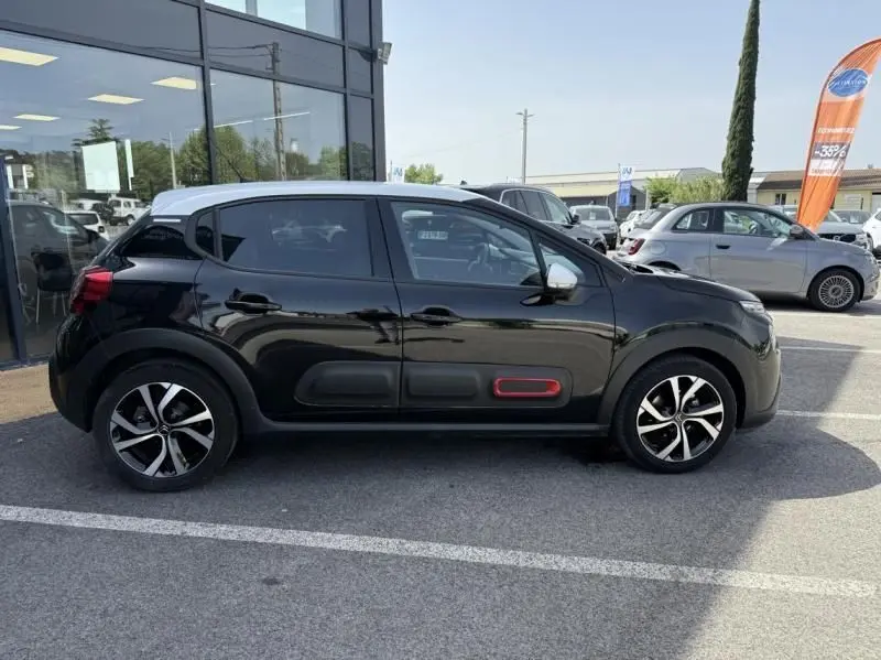 Profil côté gauche d'une Citroën C3 noire avec toit blanc, jantes alliage et inserts rouges sur les protections latérales.