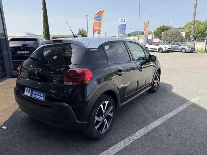 Vue 3/4 arrière droite d'une Citroën C3 2021 noire avec toit blanc, feux arrière rouges et jantes alliage bicolores.