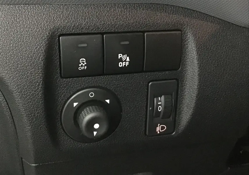 Gros plan sur les commandes de réglage des phares et de l'ESP dans l'habitacle d'un Citroën Berlingo blanc de 2018.