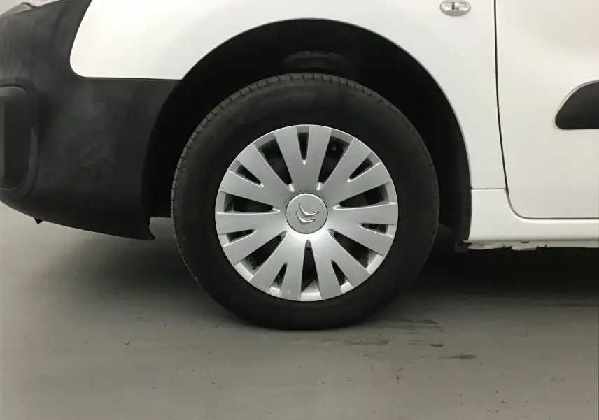 Gros plan sur la roue avant gauche blanche d'un Citroën Berlingo 2018 avec enjoliveur argenté et pare-chocs noir.