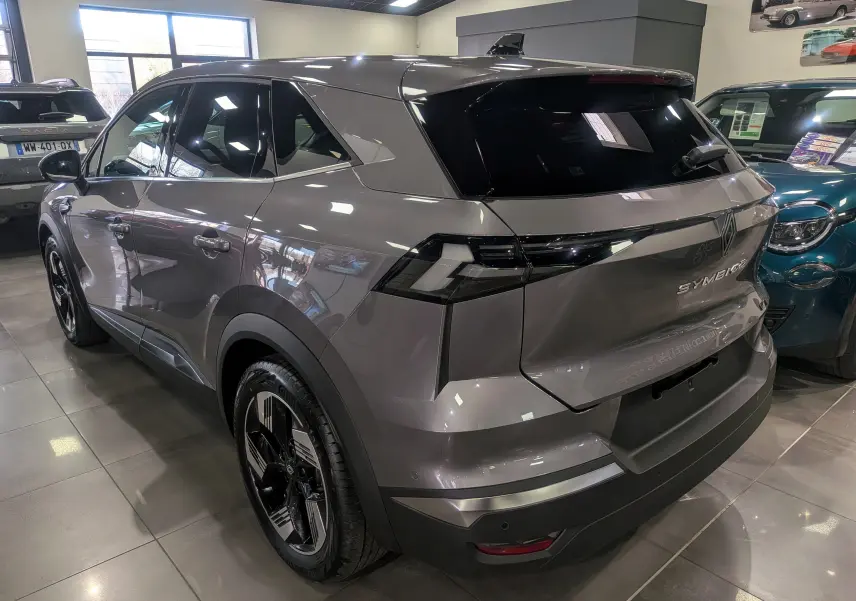 Vue 3/4 arrière droite du Renault SYMBIOZ gris Cassiopé avec feux arrière noirs et jantes bicolores en showroom.