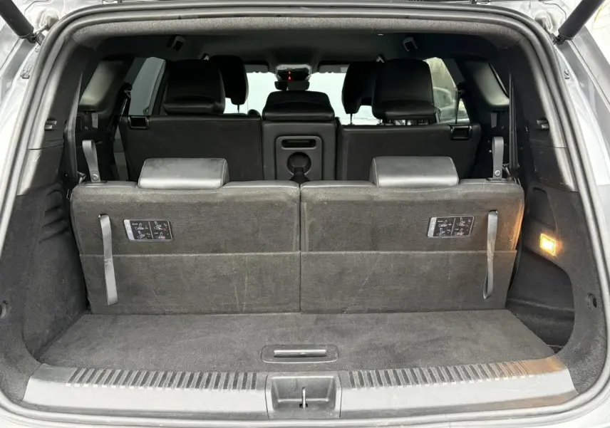 Vue arrière ouverte du coffre du Renault Espace gris, montrant la troisième rangée de sièges relevée en tissu noir.