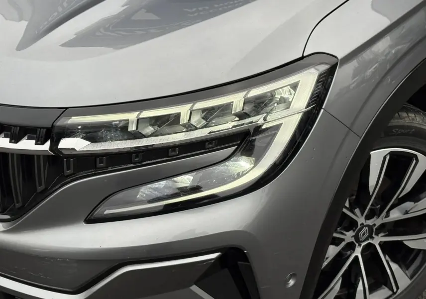 Gros plan sur le phare avant droit et la jante alliage noire diamantée du Renault Espace gris schiste 2024.