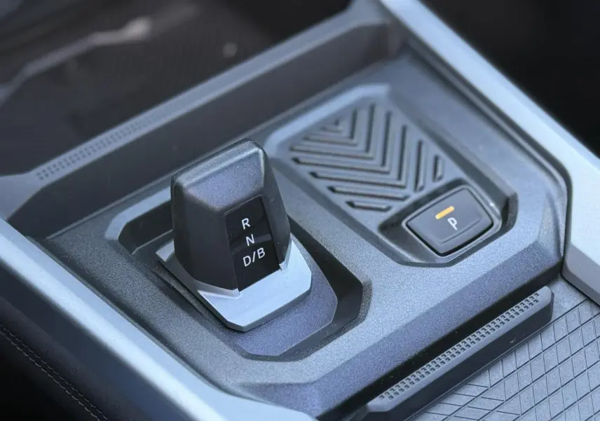 Gros plan sur la commande de boîte automatique et bouton de frein de parking du Dacia Bigster 1.8 Hybrid bleu Indigo.