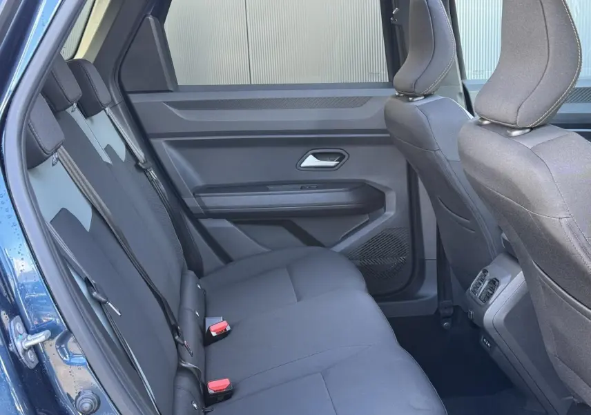 Vue intérieure côté gauche montrant la banquette arrière noire du Dacia Bigster Bleu Indigo avec portes ouvertes.