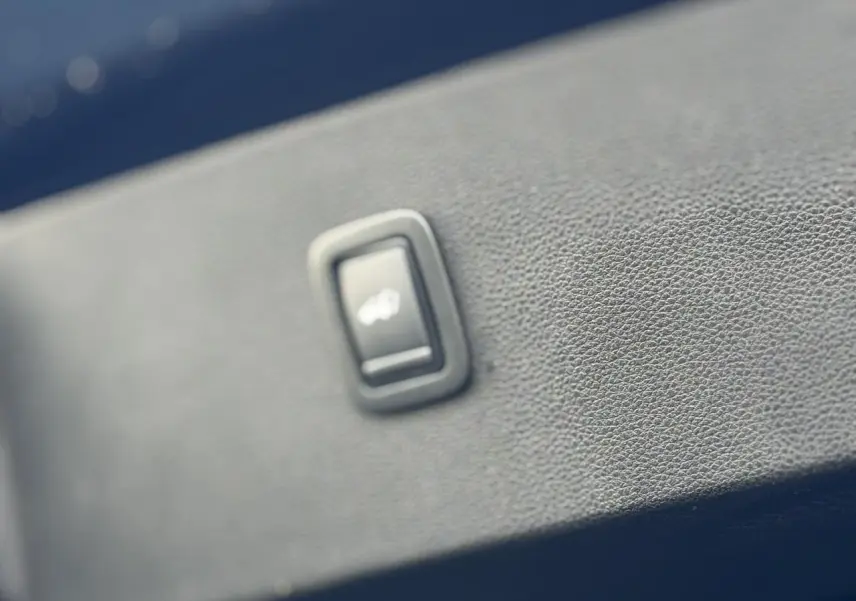 Bouton hayon électrique en gros plan sur la garniture intérieure bleu indigo du Dacia Bigster 2026.