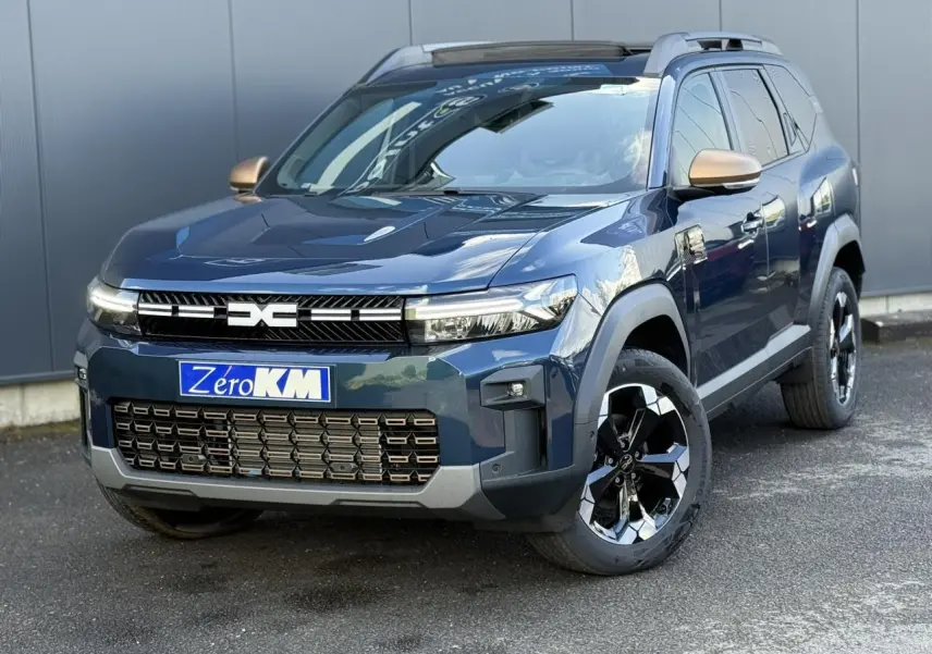 Vue 3/4 avant droit du Dacia Bigster 1.8 Hybrid bleu indigo avec jantes alliage noires et rétroviseurs dorés.