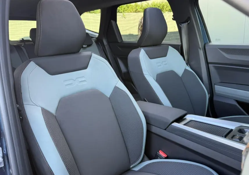 Vue intérieure sur les sièges avant gris clair et foncé du Dacia Bigster 2026 avec accoudoir central et porte-gobelets.