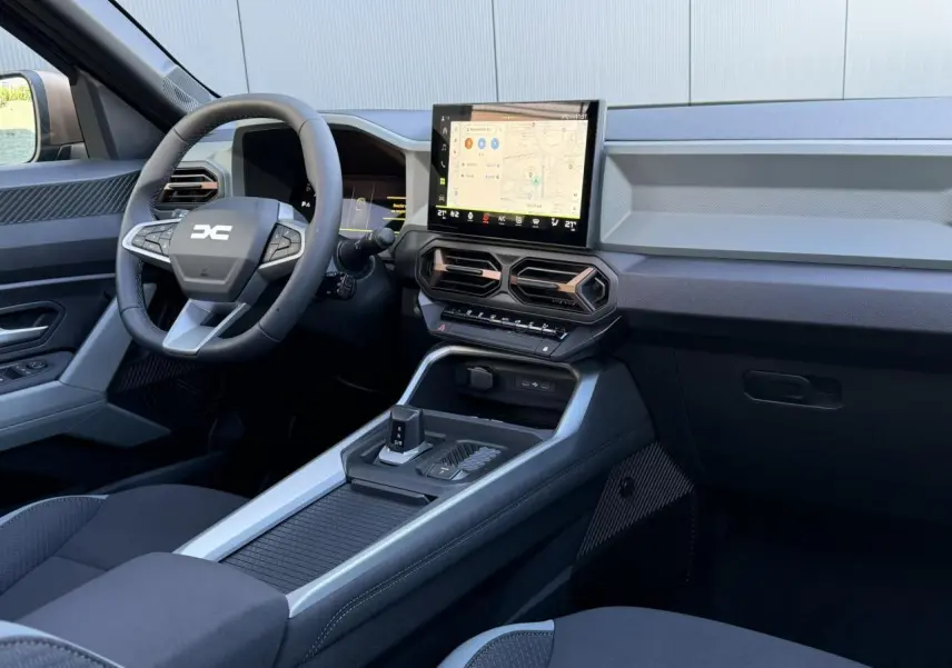 Vue intérieure côté conducteur du tableau de bord et console centrale du Dacia Bigster 2026, avec écran tactile et volant multifonction.