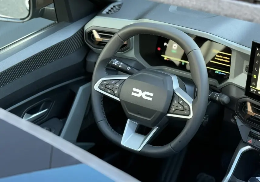 Vue rapprochée du volant multifonction noir avec logo DACIA blanc, tableau de bord numérique et partie de la console centrale du Dacia Bigster 2026.