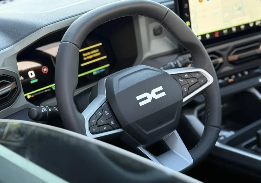 Vue rapprochée du volant noir et gris du Dacia Bigster 2026 avec tableau de bord numérique et écran tactile.