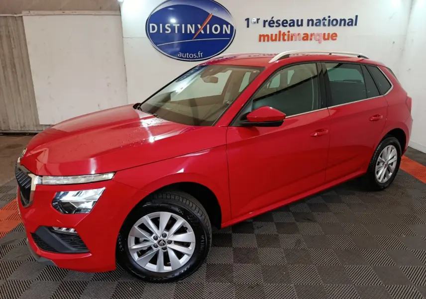 Vue 3/4 avant gauche d'un Skoda Kamiq rouge 2024 avec jantes alliage et barres de toit argentées.