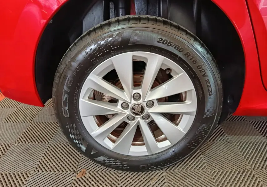 Gros plan sur la roue avant gauche d’un SKODA KAMIQ rouge, mettant en valeur la jante argentée et le pneu Ecsta.