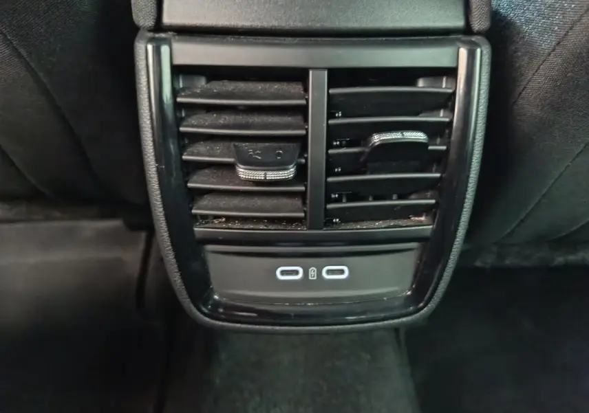 Vue rapprochée des aérateurs arrière noirs et des deux ports USB-C illuminés du Skoda Kamiq rouge 2024.