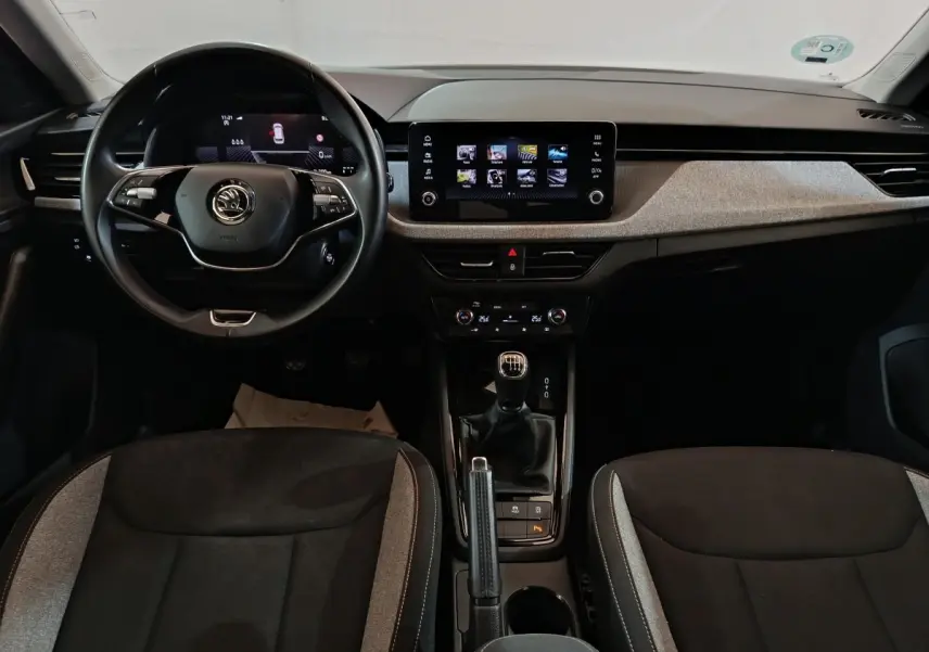 Vue intérieure frontale du tableau de bord et volant cuir multifonctions du Skoda Kamiq 2024 avec écran tactile central.