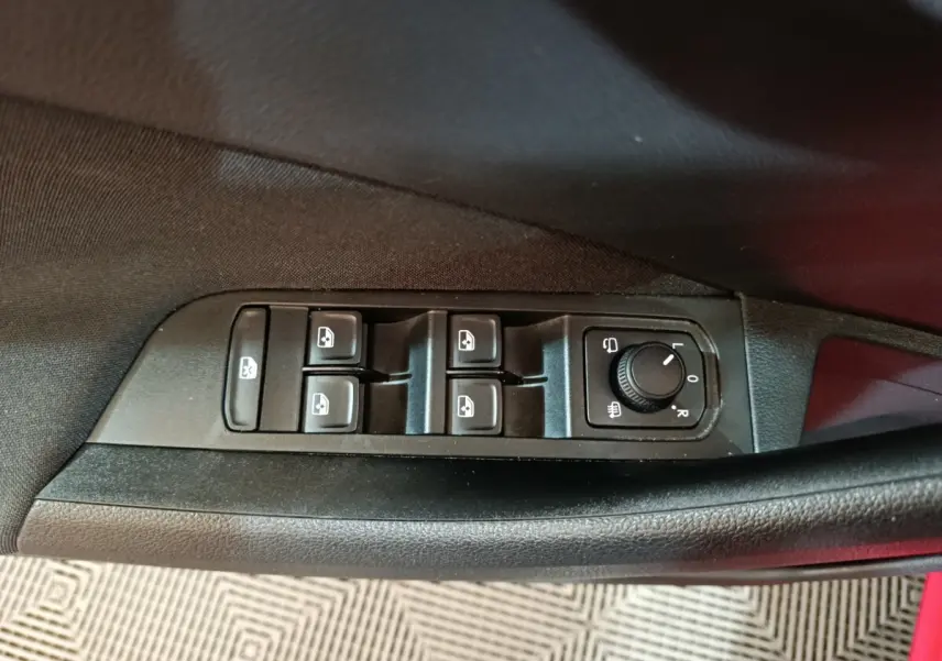 Vue rapprochée des commandes de lève-vitres et réglage des rétroviseurs côté conducteur du Skoda Kamiq rouge 2024.