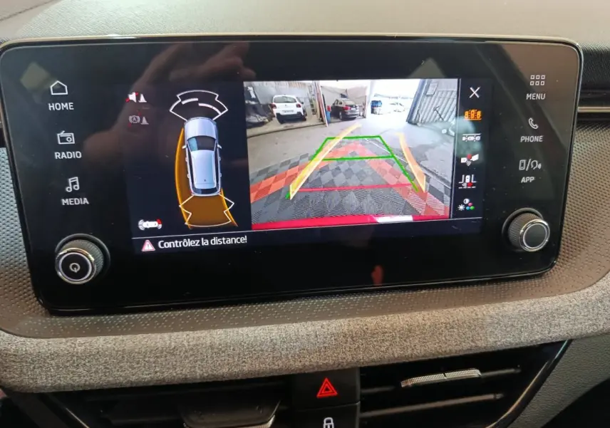 Écran tactile central du Skoda Kamiq 2024 montrant la caméra de recul avec alertes de distance et vue 360° du véhicule.