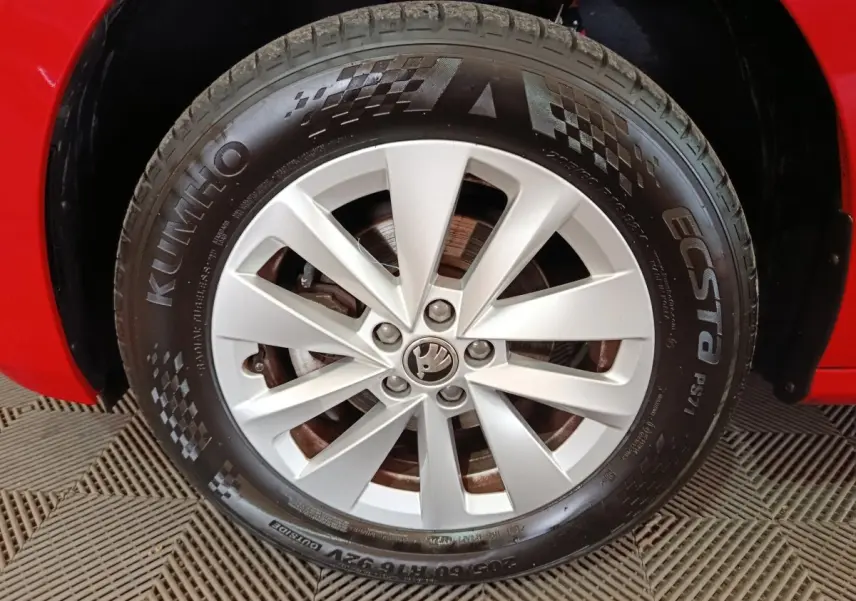 Gros plan sur la roue avant droite d’une Skoda Kamiq rouge avec jante argentée et pneu Kumho Ecsta.