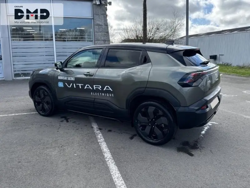 Vue 3/4 arrière droite du Suzuki Vitara électrique vert Land Breeze avec toit noir et jantes noires distinctives.