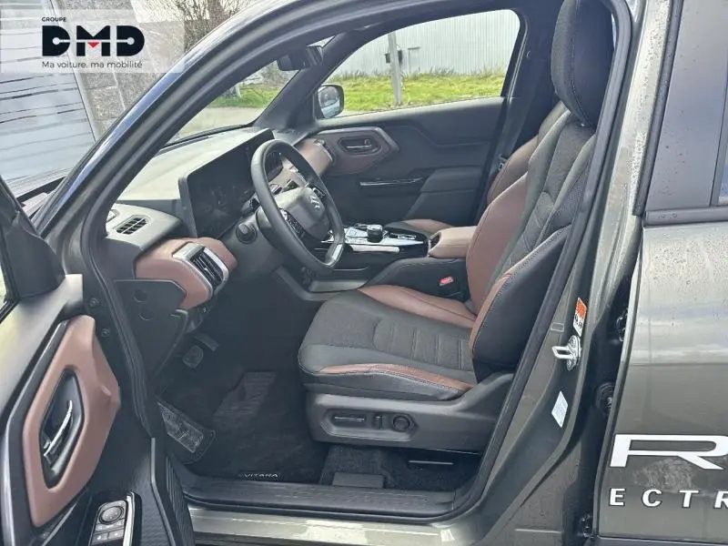 Vue intérieure côté conducteur du Suzuki Vitara 2026 avec sièges tissu/cuir noir et marron et tableau de bord moderne.