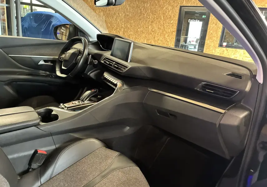 Vue intérieure côté passager du Peugeot 3008 noir, mettant en valeur le tableau de bord et la console centrale moderne.