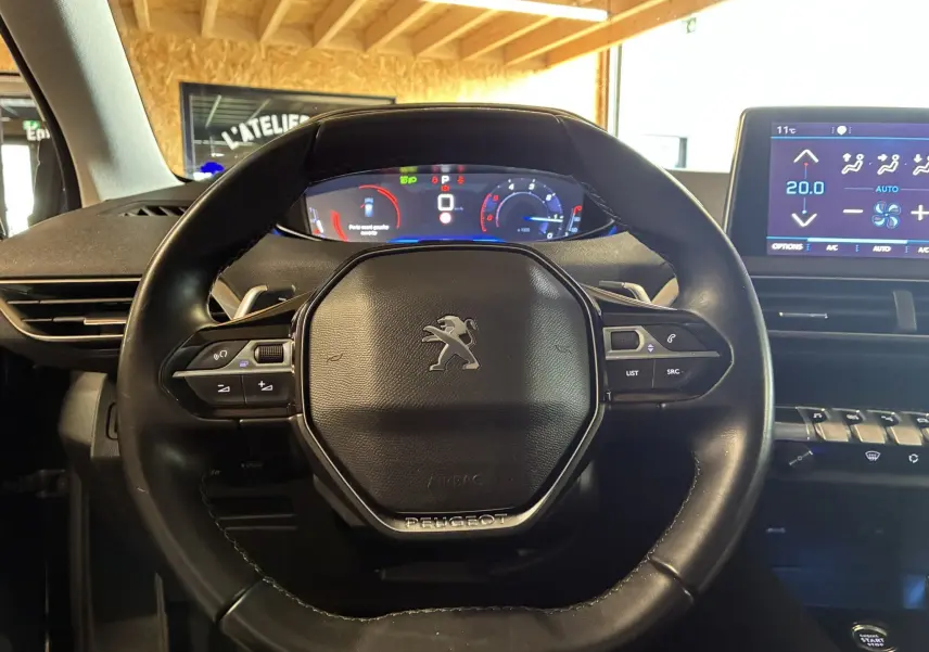 Vue intérieure centrée sur le volant noir du Peugeot 3008 1.5 BlueHDi 130 Allure Pack avec tableau de bord digital et écran tactile.