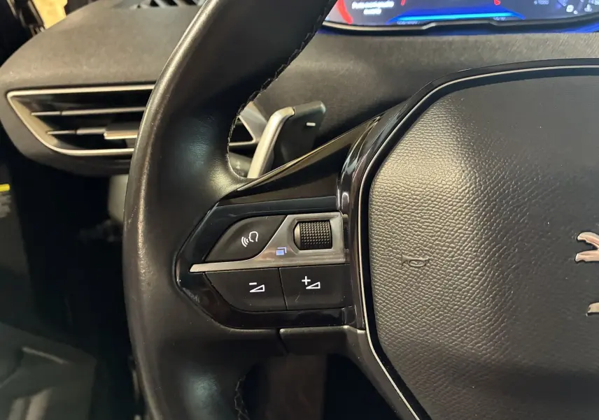 Gros plan sur le côté gauche du volant noir du Peugeot 3008 2020, avec commandes audio et volant cuir.