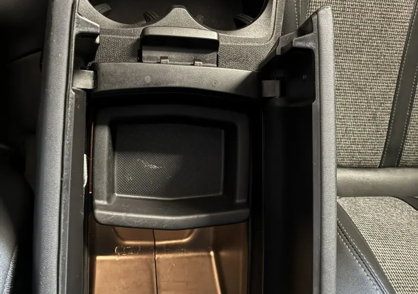 Vue plongeante sur le rangement central ouvert et porte-gobelets du Peugeot 3008 noir, intérieur tissu gris et noir.